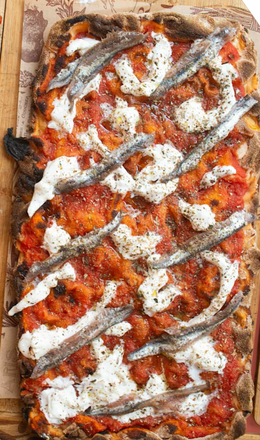 La pinsa Cetara di LORO, con burrata e alici di Cetara, sul suo tagliere di legno