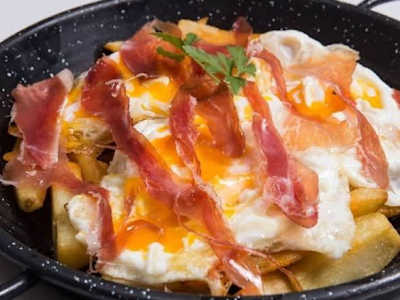 Huevos rotos con patatas, jamón y salsa de trufa